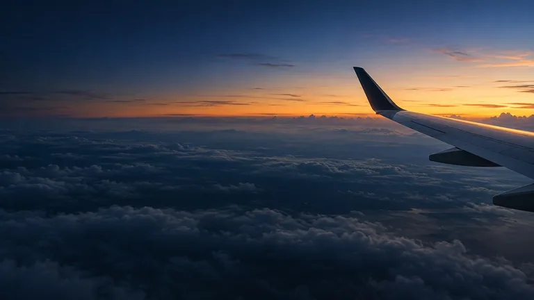 Aircraft wing above a cloud deck beneath a navy and gold dusk sky